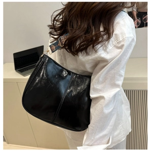 Detail of black glossy tote bag with colorful ethnic embroidered wide shoulder strap