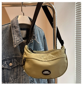 Light green crescent waist bag with Lucky Fashion patch hanging over a denim jacket