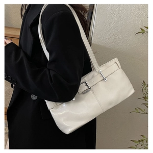 Detail of white faux leather underarm bag with decorative belt buckles and silver hardware