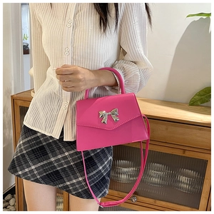 Macro view of hot pink small square bag with silver metallic bow and elegant top handle