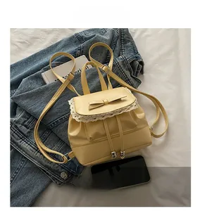 Détail du mini sac à dos jaune avec bordure en dentelle et nœud sur denim