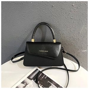 Detail view of black PU leather handbag with golden FASHION & BAGS lettering and textures