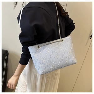Close-up of light blue embroidered tote bag with white floral pattern and gold chain strap