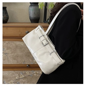 White glossy patent leather underarm bag with silver buckle worn by a model in a suit