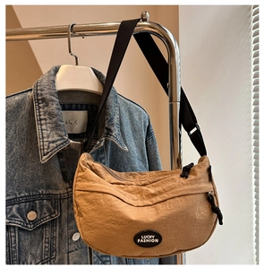 Detail of khaki crescent crossbody bag with water-resistant nylon texture and logo label