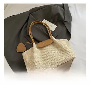 Detail view of woven straw tote bag with brown leather accents on a grey blazer suit