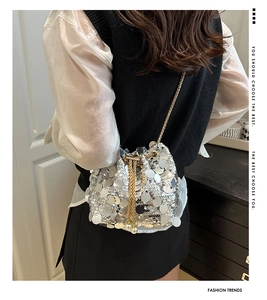 Detail of silver sequin bucket bag featuring a gold chain and pearl drawstring closure