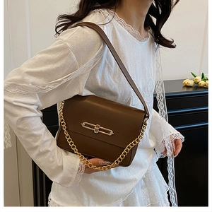 Detailed view of the dark brown leather shoulder bag featuring a gold chain and bar lock