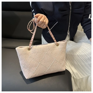 Detail of pink quilted tote bag with gold chain strap and textured tweed fabric
