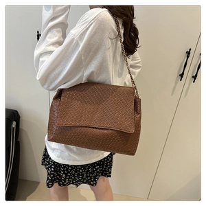 Detail of a brown woven texture shoulder bag with champagne gold chain strap for women