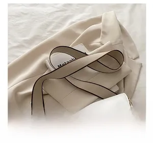 Détail du sac demi-lune blanc avec motif de touches de piano et bandoulière large