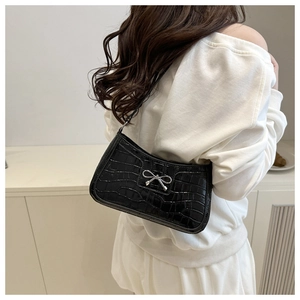 Détail d'un sac à bandoulière noir effet crocodile avec boucle en métal en nœud argenté