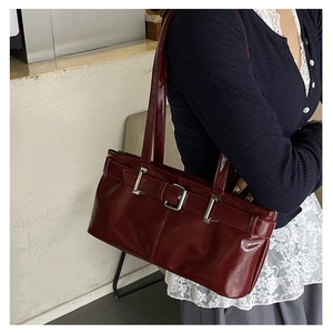 Detail of burgundy patent leather shoulder bag with silver buckle and glossy finish