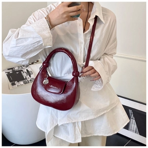 Close-up of a dark red crescent handbag with smooth leather and elegant white lettering