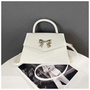 Detail of white leather handbag with shiny silver bow clasp and elegant thin strap