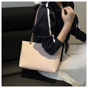 Close-up of pink tweed tote bag with white quilted pattern and metal chain strap on model