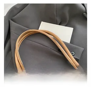 Detailed close-up of straw tote bag with leather handle and woven white stitching