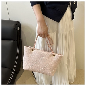 Detail of light pink tweed tote bag showing woven texture and gold chain straps