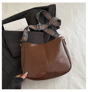 Detail of vintage brown tote bag with colorful ethnic style woven shoulder strap on suit