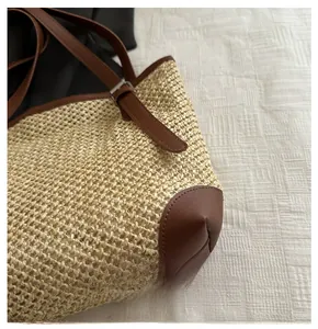 Detail of woven straw tote bag with reinforced brown leather corners and fine stitching