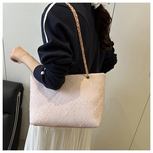 Detail of pink tote bag with floral embroidery and gold metal chain strap on model shoulder