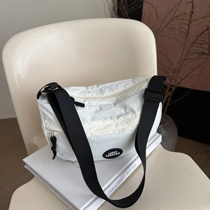 Borsa a tracolla minimalista in nylon plissettato bianco con tracolla nera su sedia