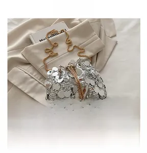 Detail of silver sequin bucket bag with pearl drawstring charms and gold chain strap