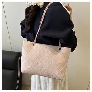 Détail du sac cabas brodé rose clair avec chaîne dorée élégante et tissu à texture riche