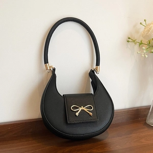 Minimalist black hobo shoulder bag with a gold bow buckle and cross-grain leather texture