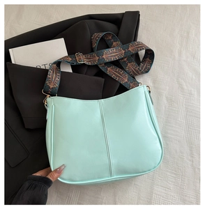 Detail of mint green crossbody bag featuring a retro geometric patterned wide strap