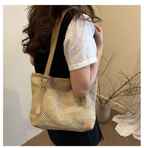 Detail of hand-woven straw tote bag featuring leather edges and adjustable shoulder strap