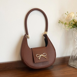 Detail of crescent moon bag in brown crossgrain leather with golden bow metal clasp