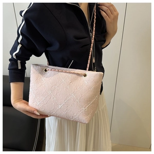 Detail of pink woven tweed tote bag featuring white plaid pattern and gold chain strap