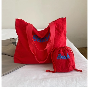 Detail of red canvas tote bag set with Beach typography and matching drawstring pouch