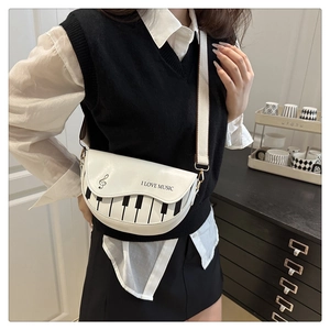 Détail d'un sac selle blanc avec motif clavier de piano et bandoulière en tissu