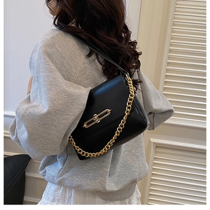 Détail du sac à bandoulière en cuir noir avec chaîne dorée et fermoir métallique chic