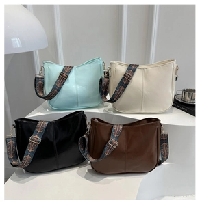 Detail of minimalist leather crescent bags with ethnic style patterned wide shoulder straps