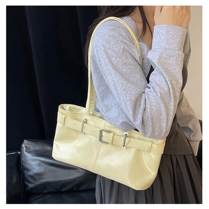 Chic light yellow leather shoulder bag with buckle detail worn by model on shoulder