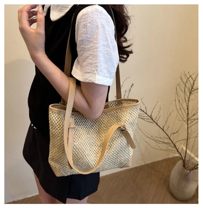 Detail of the woven mesh straw tote bag with khaki leather straps and metal buckle