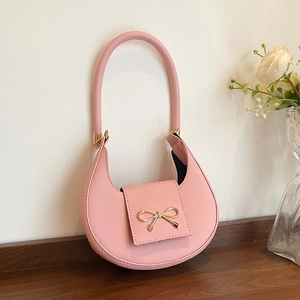 Detail of pink crescent bag featuring a golden metal bow and fine textured leather