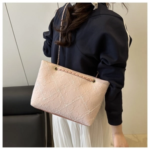 Close-up of pink quilted tote bag with golden chain strap on a model shoulder