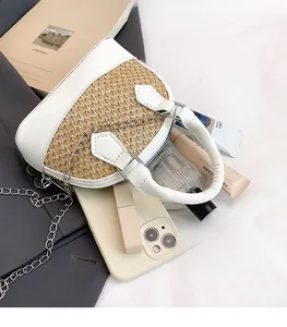 Detail view of woven straw and white leather shell bag showing spacious interior storage
