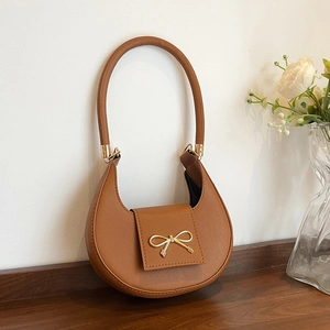 Close-up of brown Saffiano leather underarm bag with a golden bow metal buckle