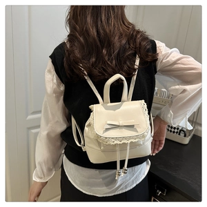 Vue détaillée du sac à dos blanc crème avec bordure en dentelle et nœud en cuir élégant