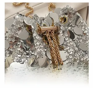 Detail of silver sequin bucket bag with gold chain strap and drawstring closure