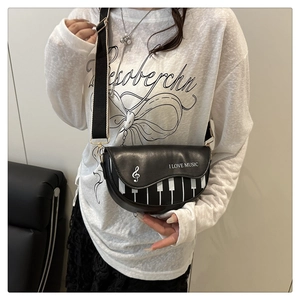 Détail du sac de selle noir avec motif de touches de piano et large bandoulière