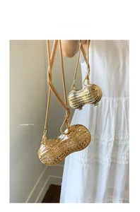 Dettaglio borsa da sera dorata a forma di arachide con strass bianchi e catena a serpente