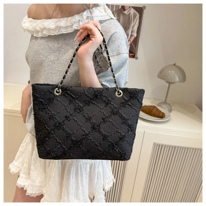 Chic black quilted tote bag with metallic chain strap worn by a model in a stylish setting
