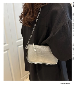 Sac bandoulière argenté texture crocodile avec chaîne métallique porté sur un vêtement