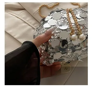 Close-up of silver sequin handbag with gold chain strap and pearl drawstring charms